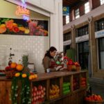 A vibrant juice bar inside a historic market with fresh fruits displayed.