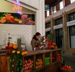 A vibrant juice bar inside a historic market with fresh fruits displayed.