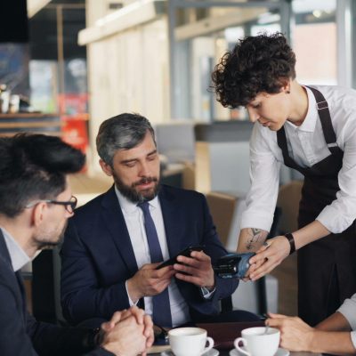 Business professionals in a cafe settling payment with a waiter.