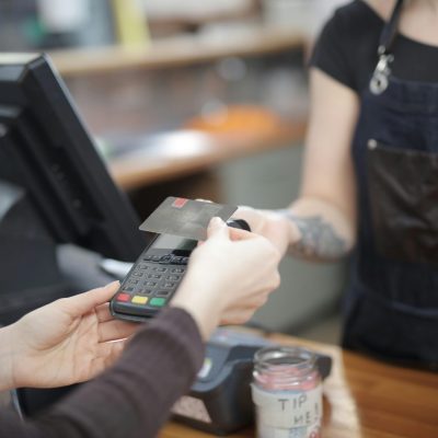 Close-up of customer and cashier during a credit card transaction at a store counter indoors.